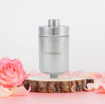 Chic SUPERPURE Satin Chrome Shower Filter positioned on a rustic wooden stand amidst soft rose petals, enhancing your shower experience