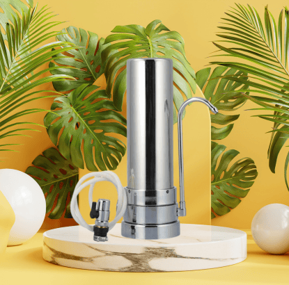 Sleek SUPERPURE Stainless Steel Counter-Top Water Filtration Unit with attached faucet and GAC filter, set against a vibrant background with tropical leaves and decorative spheres.